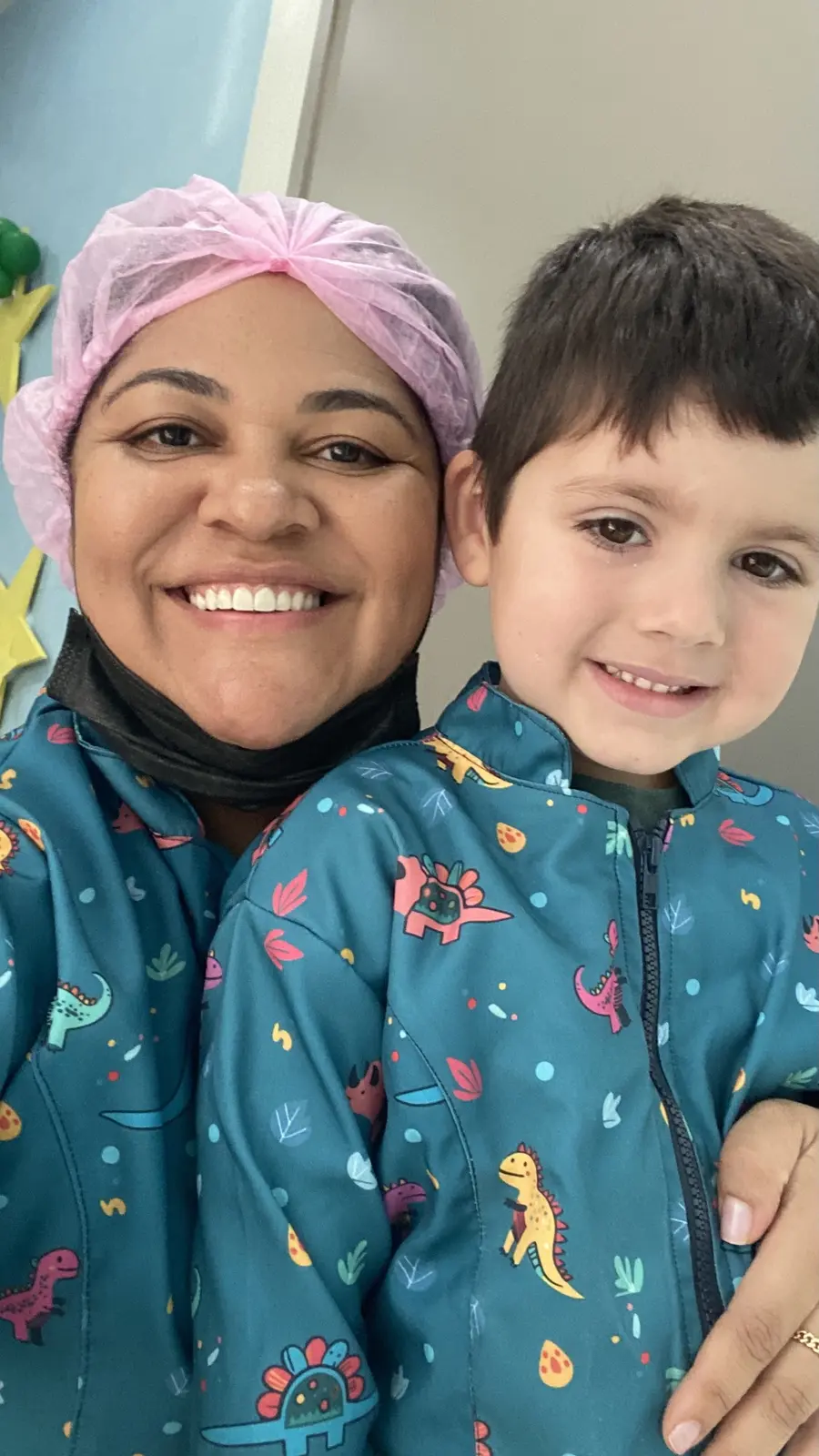 Dra. Alda e um paciente pequeno, os dois com jaleco de dinossauros