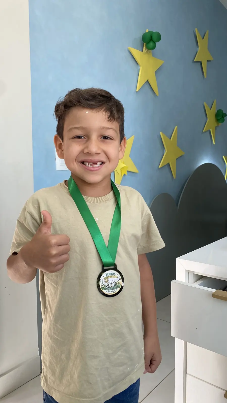 Menino com medalha no peito fazendo sinal de positivo
