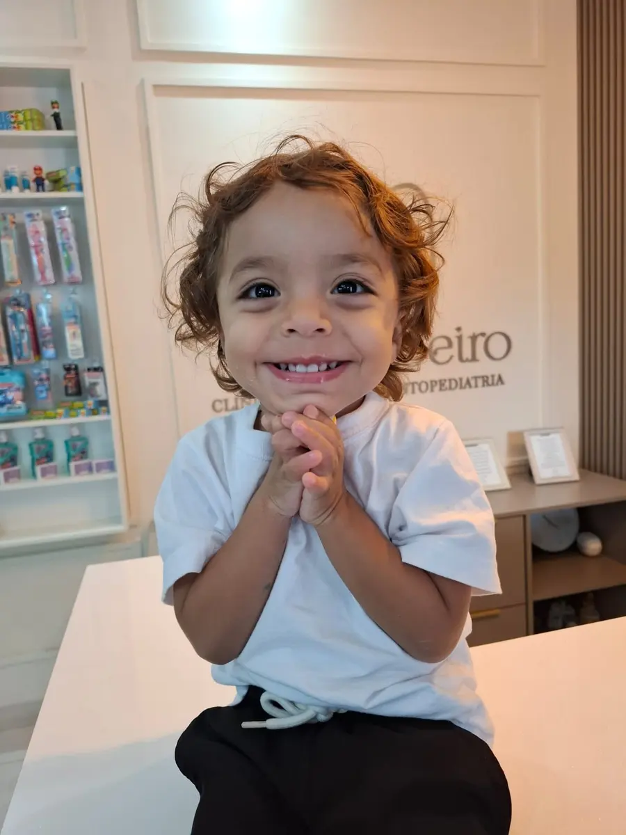 Criança sorrindo sentada no balcão da recepção
